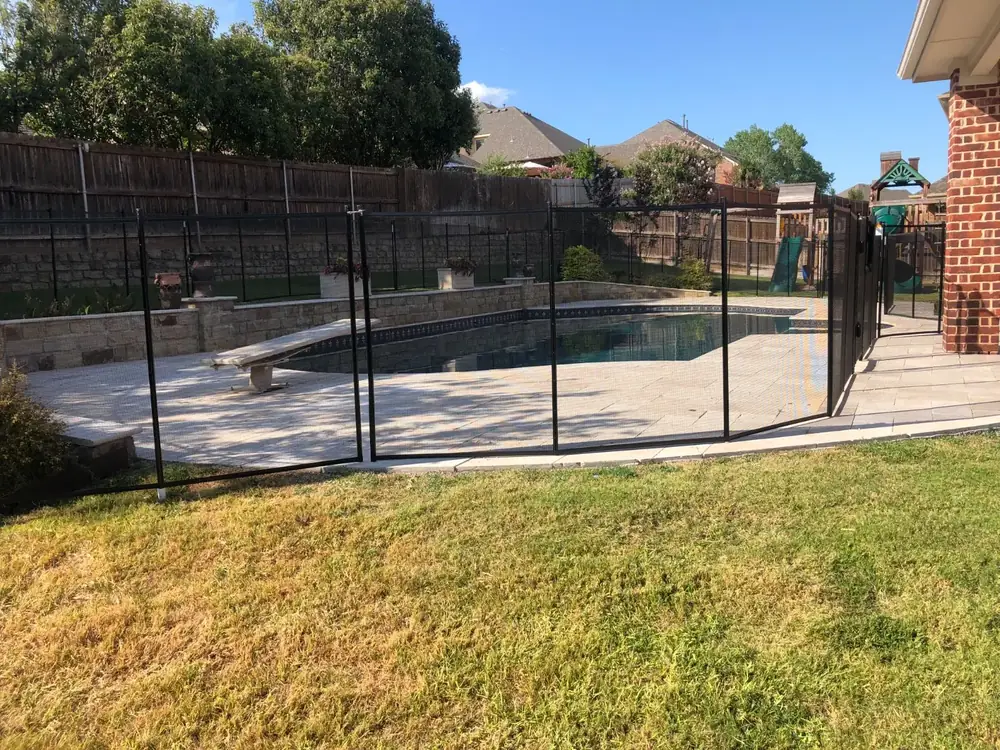 Black mesh safety fence around a backyard pool