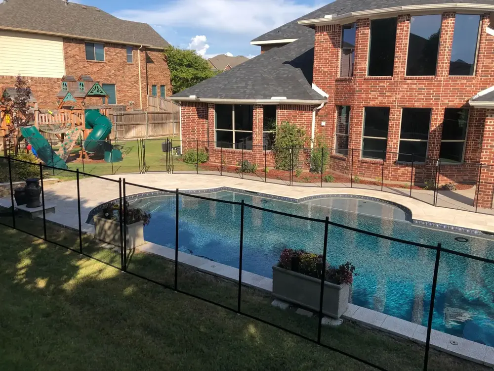 Black mesh safety fence around a backyard pool