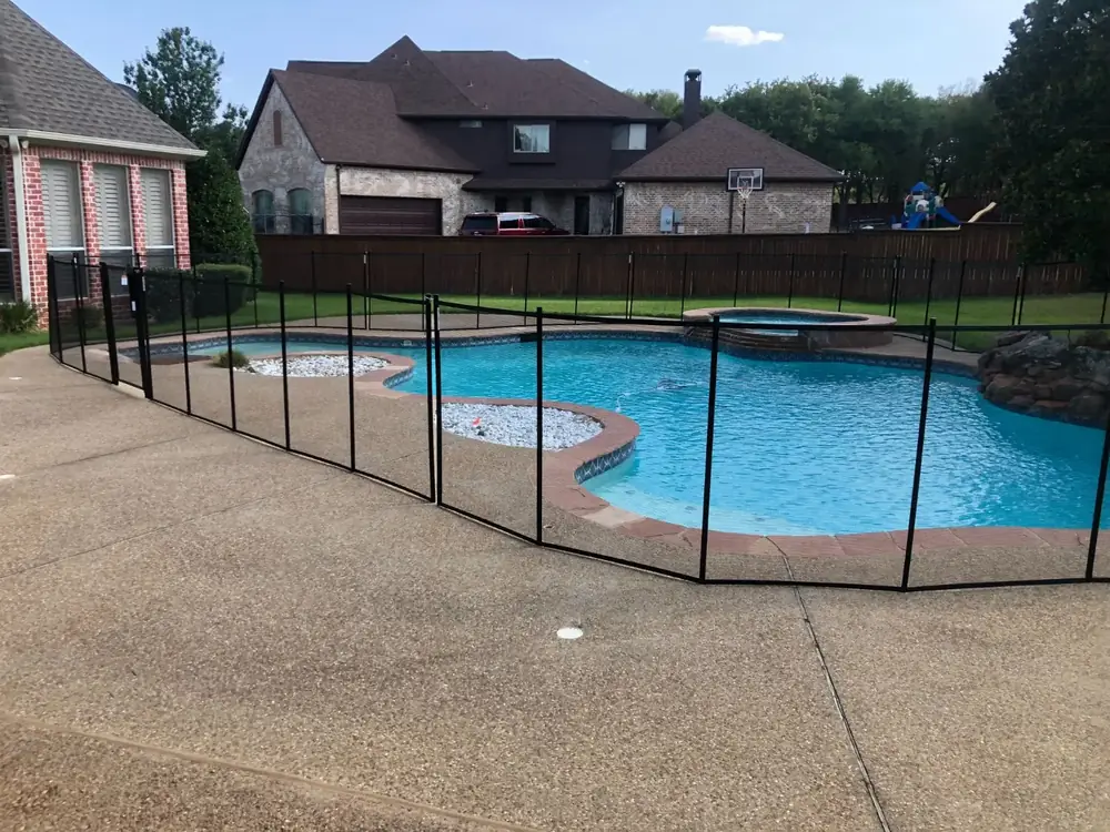 Black mesh safety fence around a backyard pool