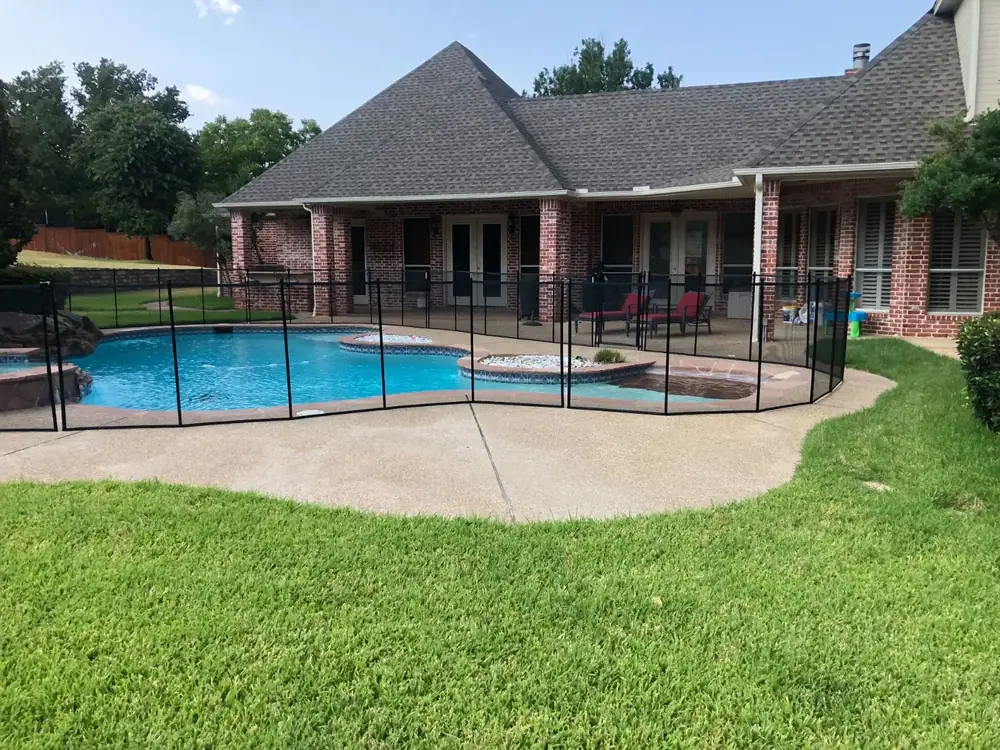 Black mesh safety fence around a backyard pool