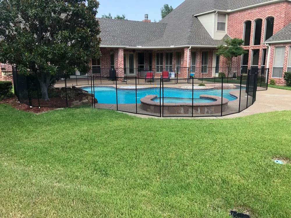Black mesh safety fence around a backyard pool