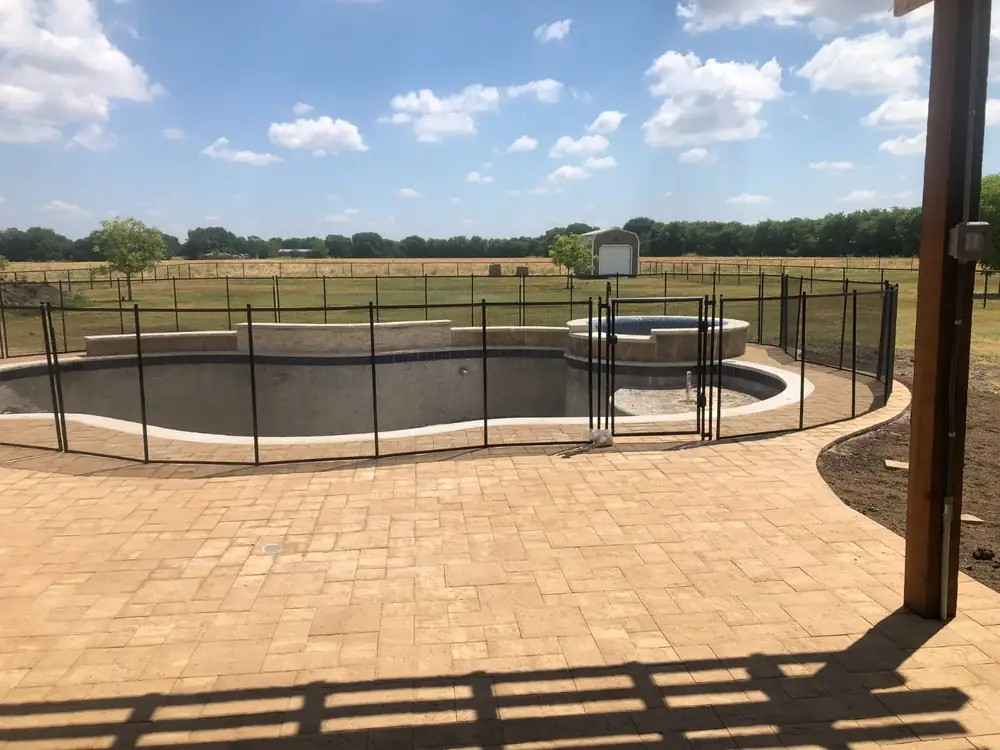 Black mesh safety fence around a backyard pool