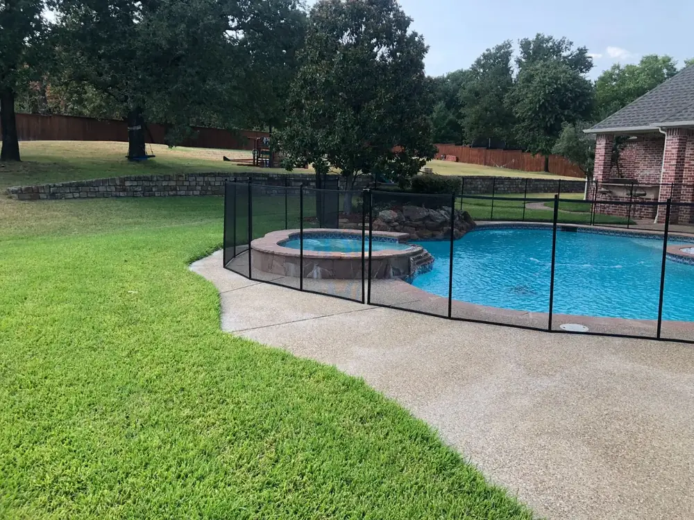 Black mesh safety fence around a backyard pool