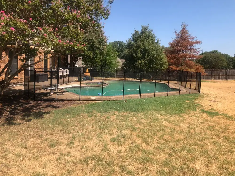 Black mesh safety fence around a backyard pool