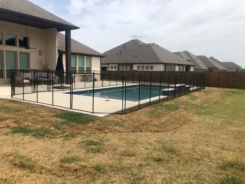 Black mesh safety fence around a backyard pool