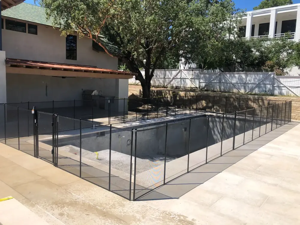 Black mesh safety fence around a backyard pool
