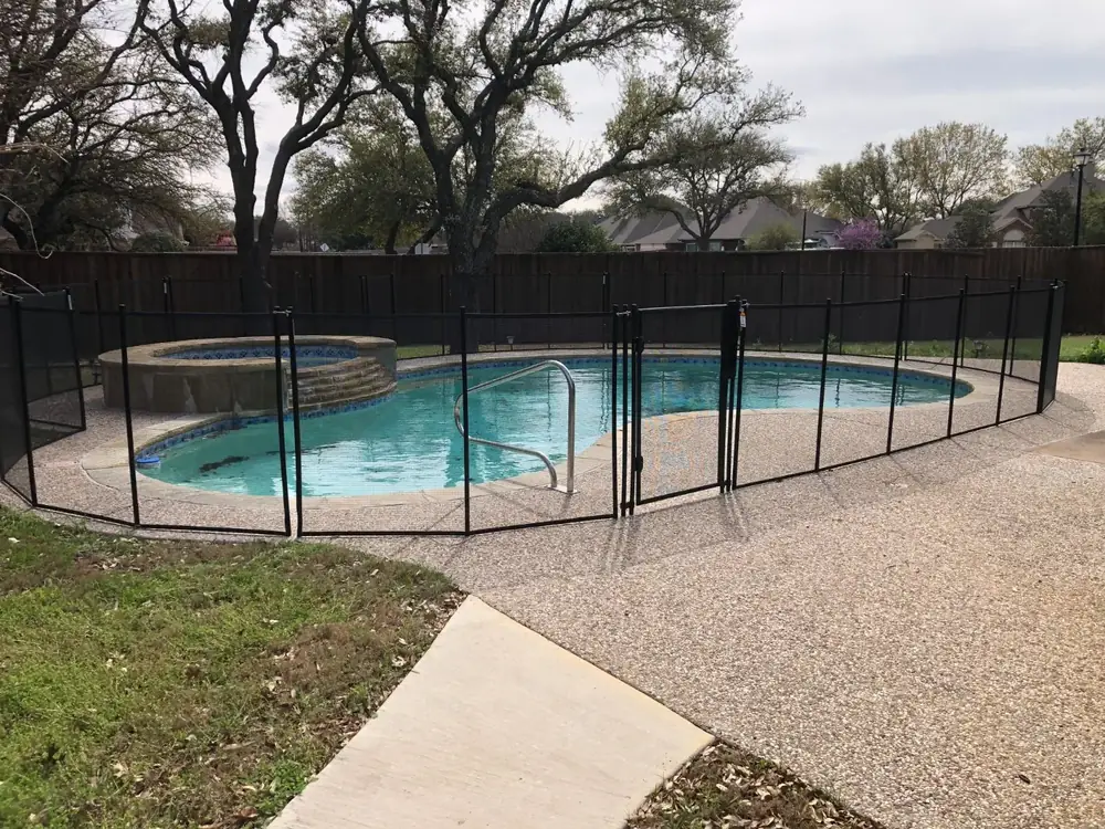 Black mesh safety fence around a backyard pool