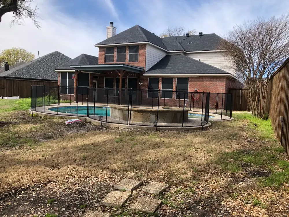 Black mesh safety fence around a backyard pool