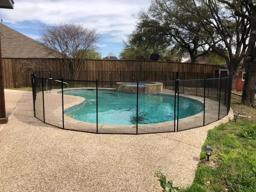 Black mesh safety fence around a backyard pool
