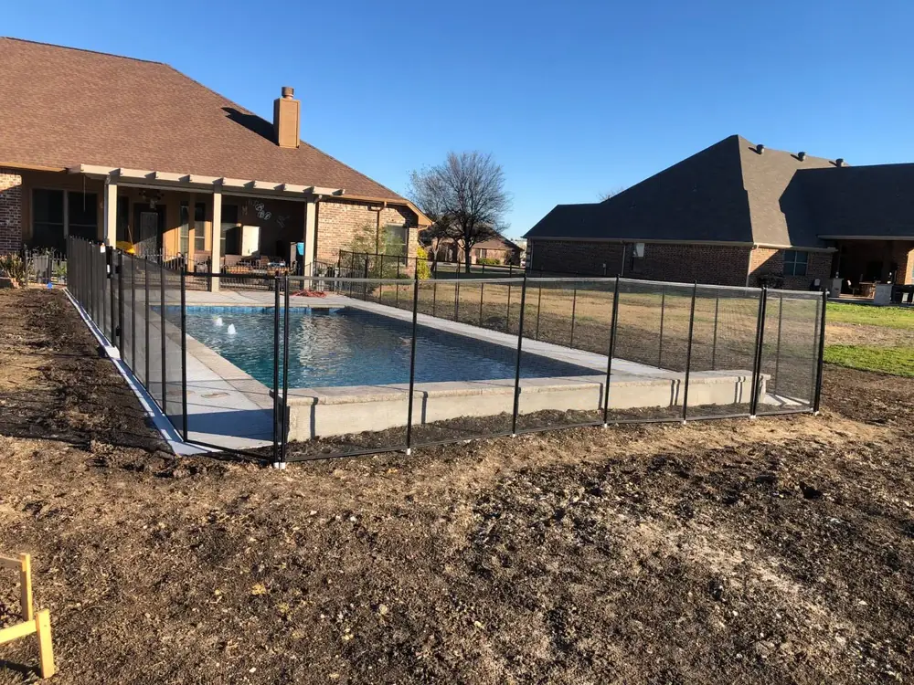 Black mesh safety fence around a backyard pool