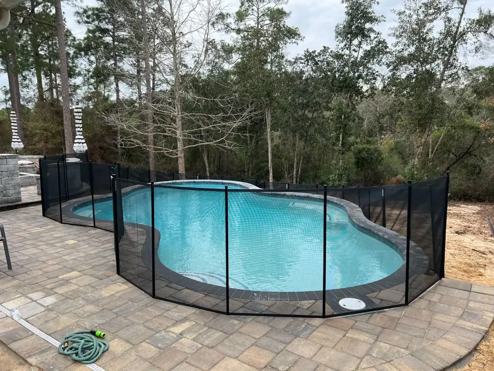 Black mesh safety fence around a backyard pool