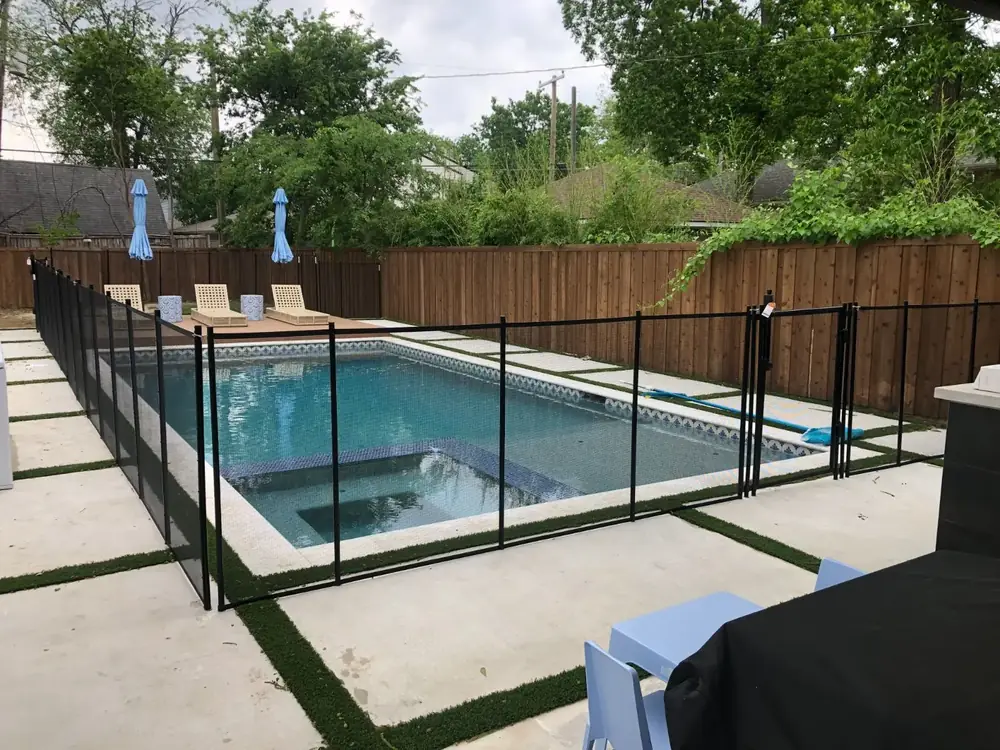 Black mesh safety fence around a backyard pool