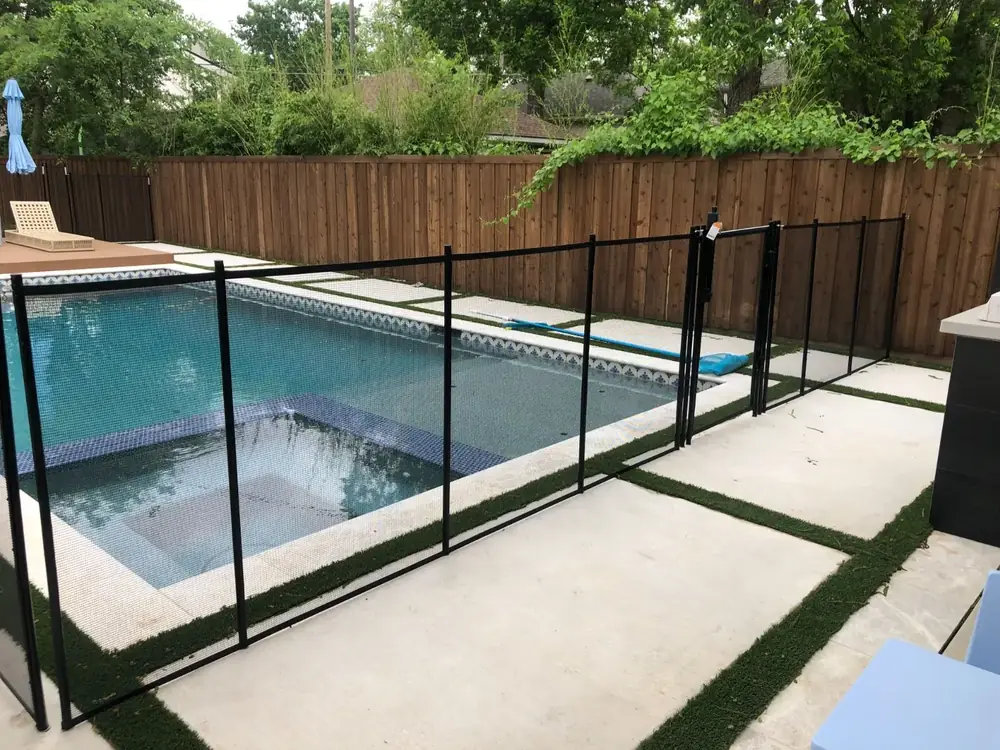 Black mesh safety fence around a backyard pool