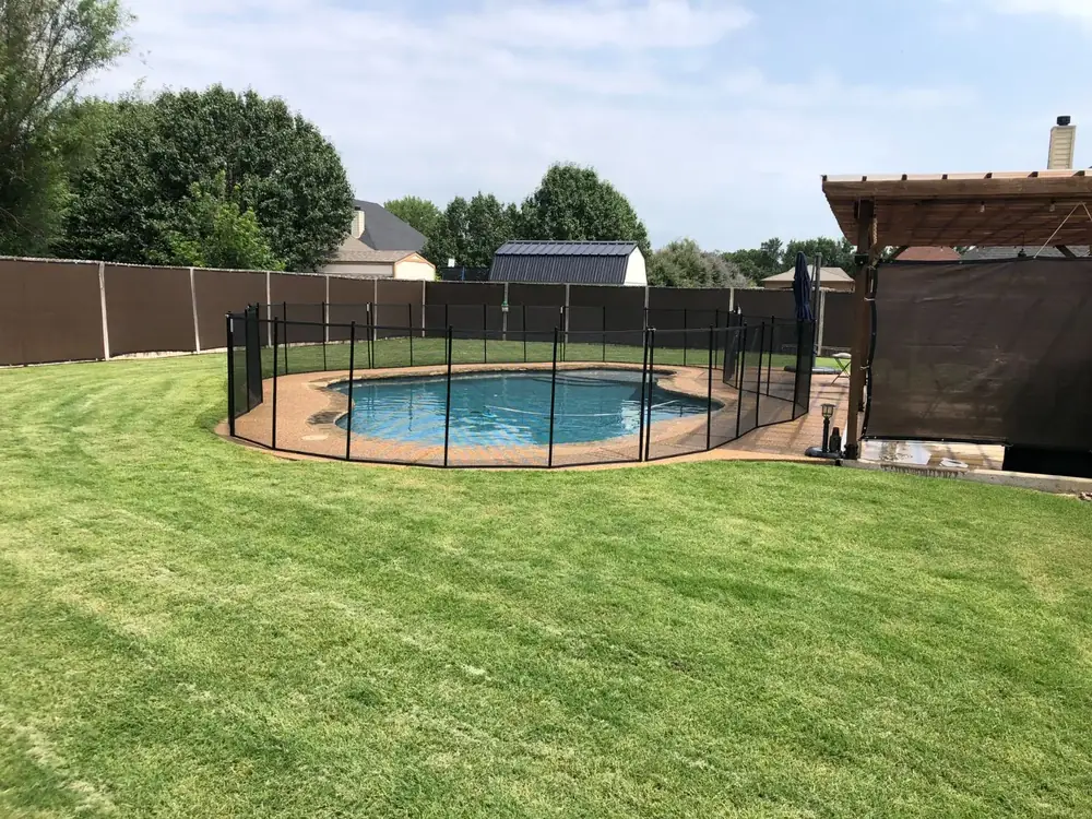 Black mesh safety fence around a backyard pool