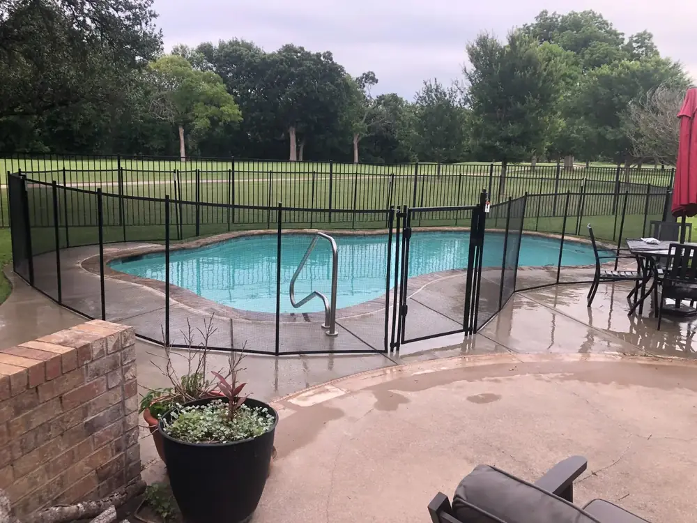 Black mesh safety fence around a backyard pool