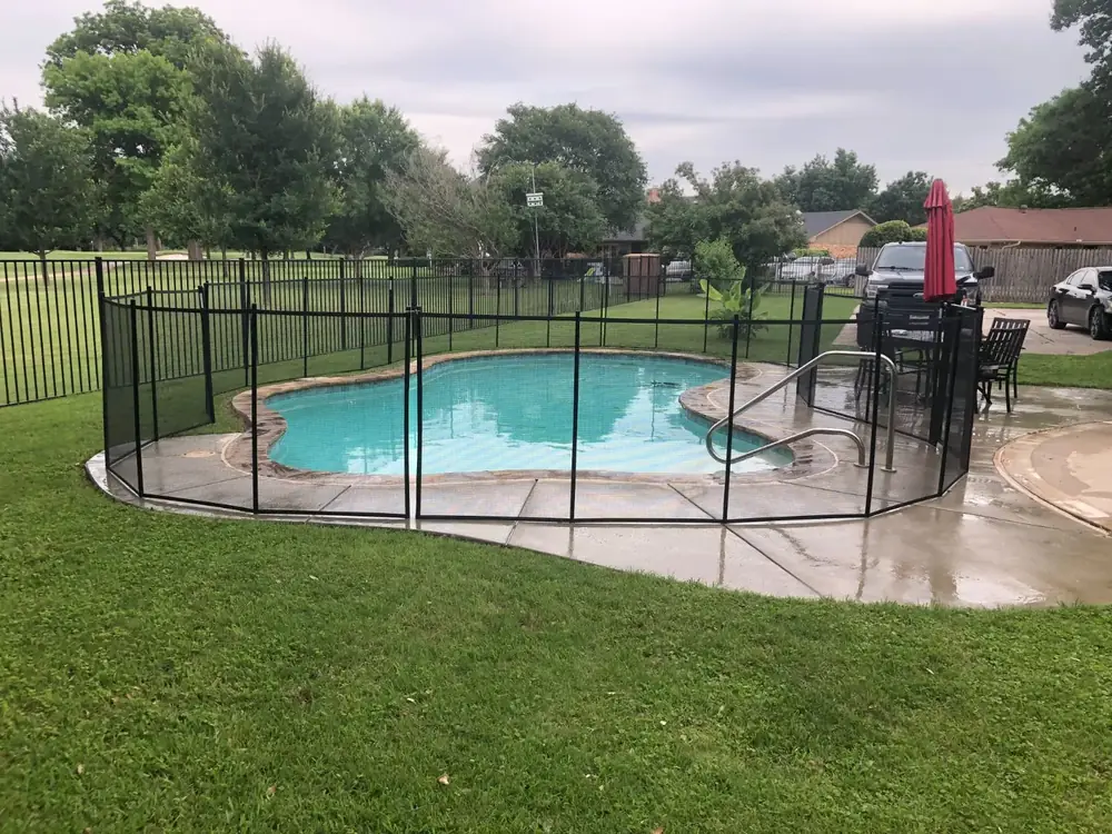 Black mesh safety fence around a backyard pool