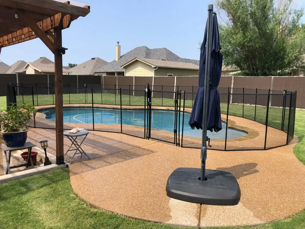 Black mesh safety fence around a backyard pool
