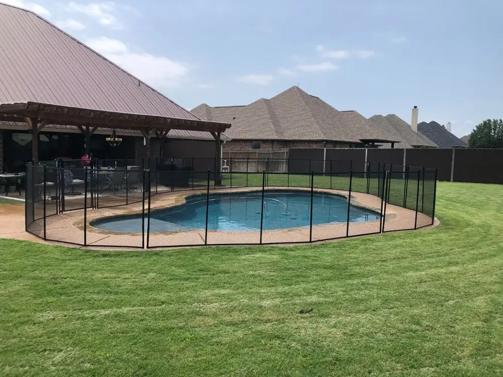 Black mesh safety fence around a backyard pool