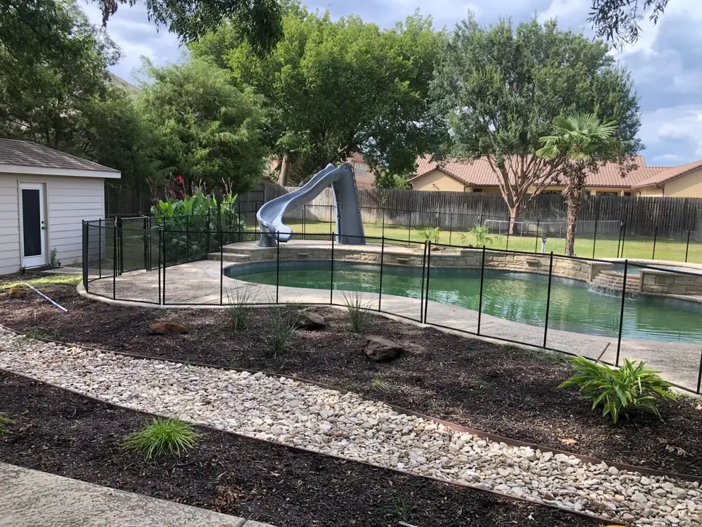 Black mesh safety fence around a backyard pool