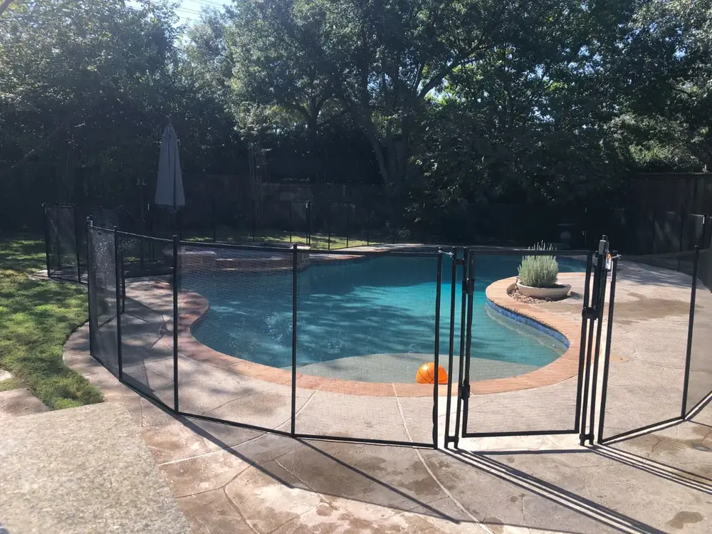 Black mesh safety fence around a backyard pool
