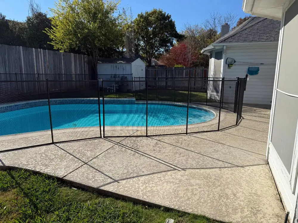 Black mesh safety fence around a backyard pool