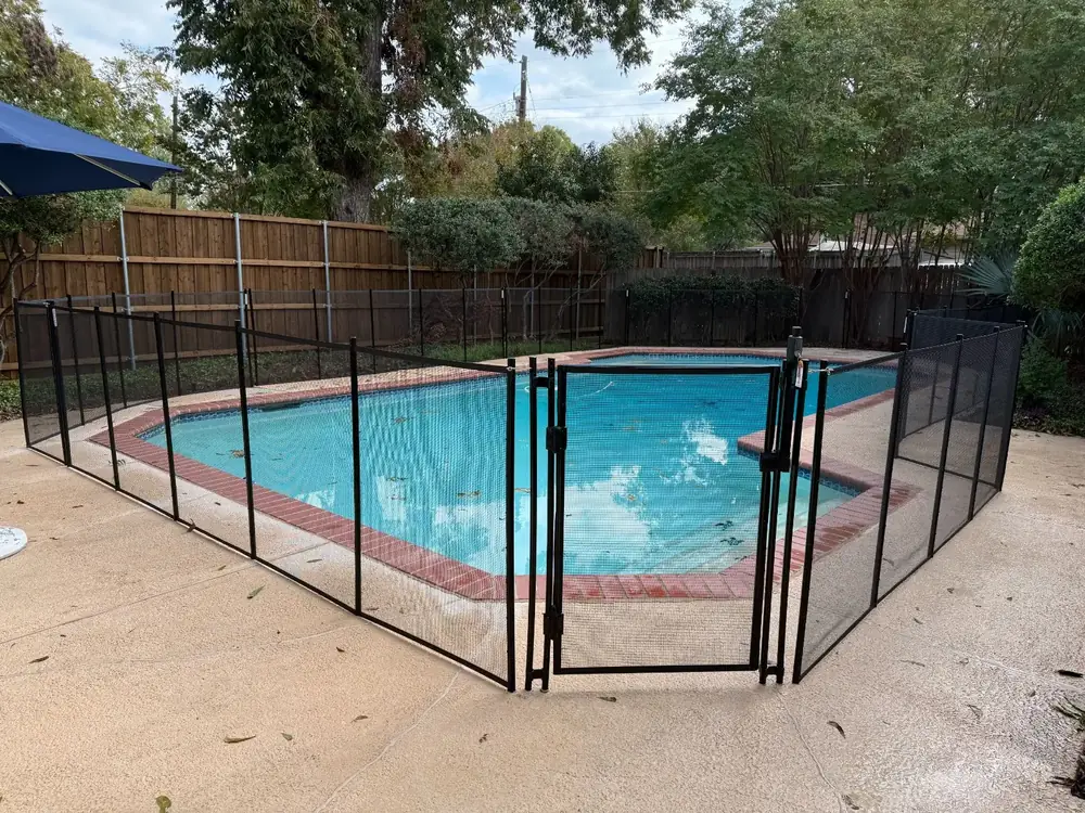 Black mesh safety fence around a backyard pool