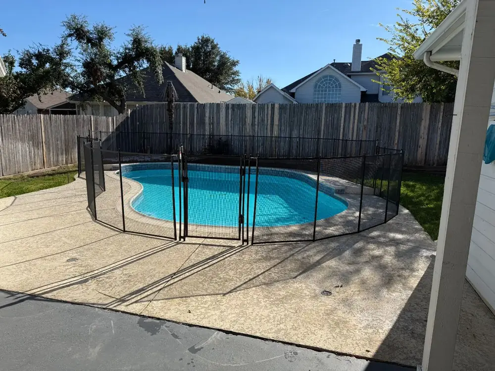 Black mesh safety fence around a backyard pool