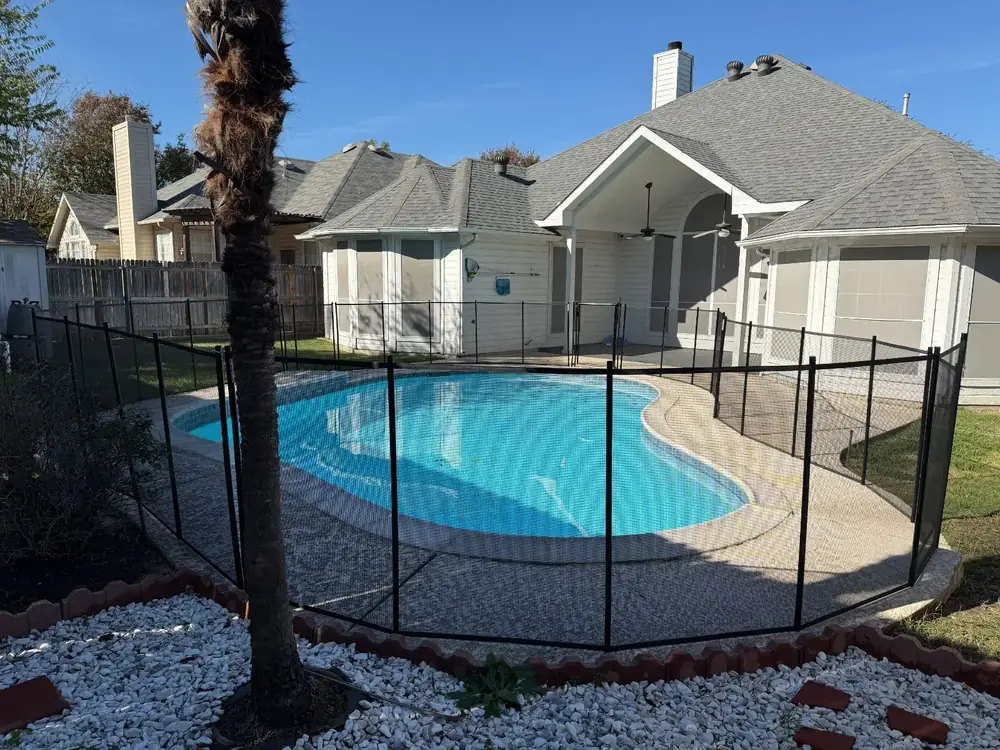 Black mesh safety fence around a backyard pool