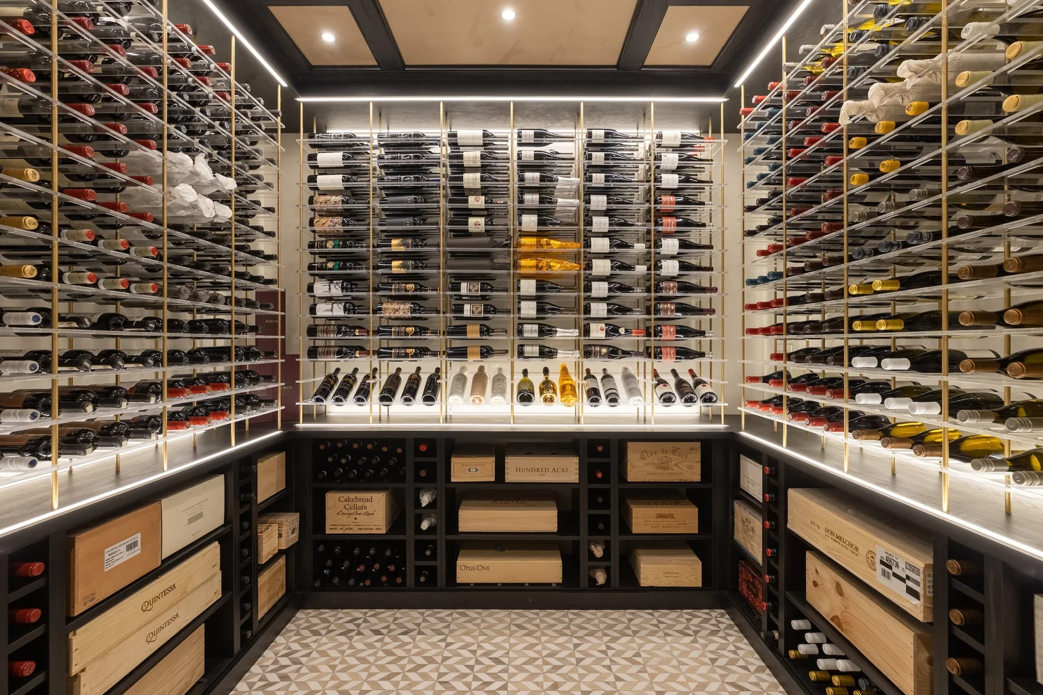 Custom wine cellar with wood racking, integrated lighting, and a glass door built into the lower level of a large McLean, Virginia estate home. The finished space connects to an adjacent tasting area with refined cabinetry and stone flooring.