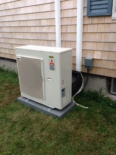 Ductless heat pump outdoor unit against home siding
