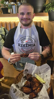 Man wearing a bib, holding a chicken wing, preparing to eat Man wearing a bib, holding a chicken wing, preparing to eat