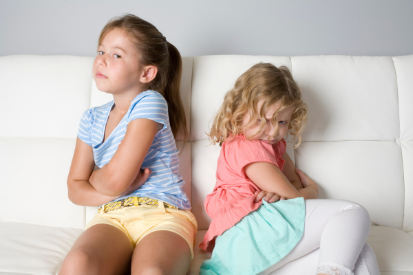 Two girls pouting with their backs to one another after an arguement. Two girls pouting with their backs to one another after an arguement.