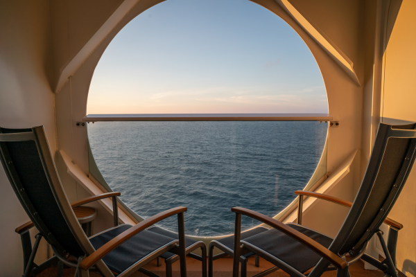 Two chairs by a porthole window looking out to sea Two chairs by a porthole window looking out to sea