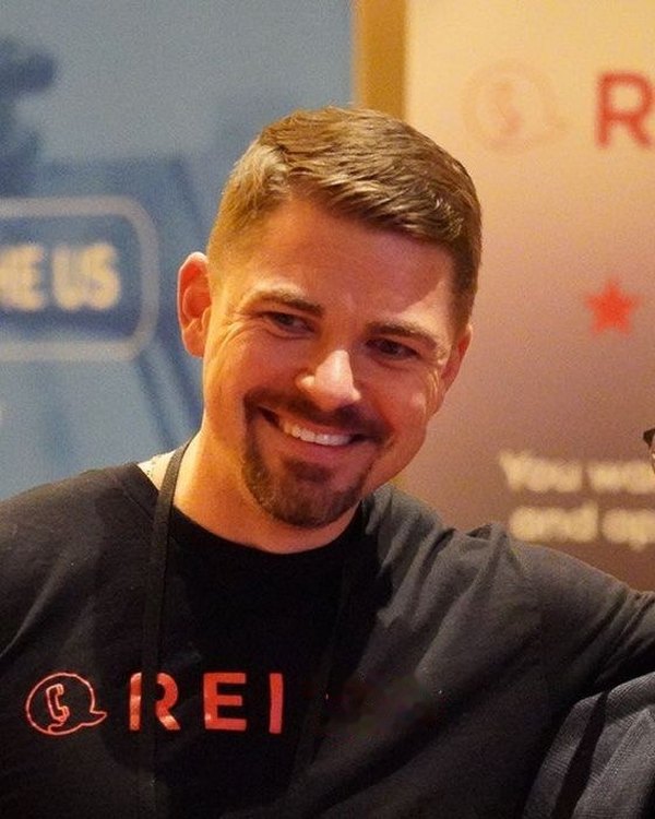 Anton Zherelyev smiling at an industry event in an REI shirt