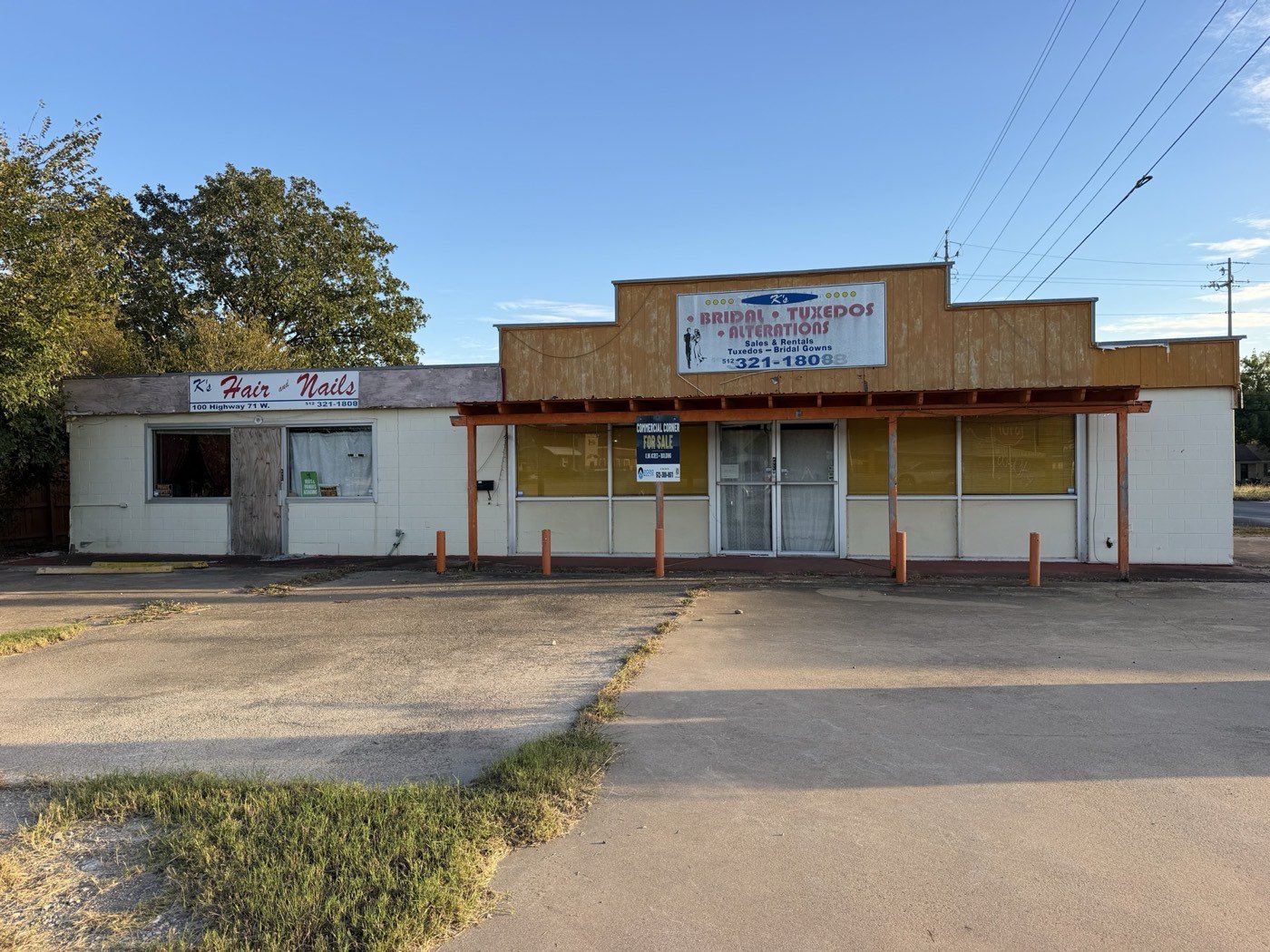 Front of the existing building under the covered walkway with the For Sale sign