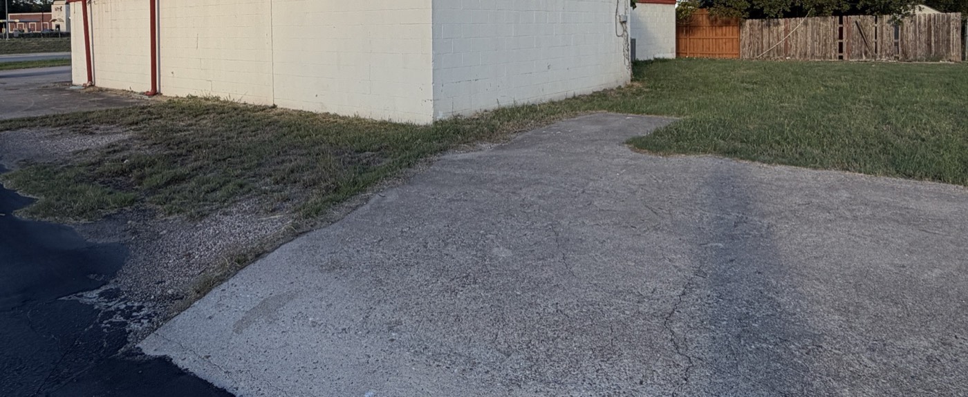Rear of the building with a wood fence and open lawn behind it