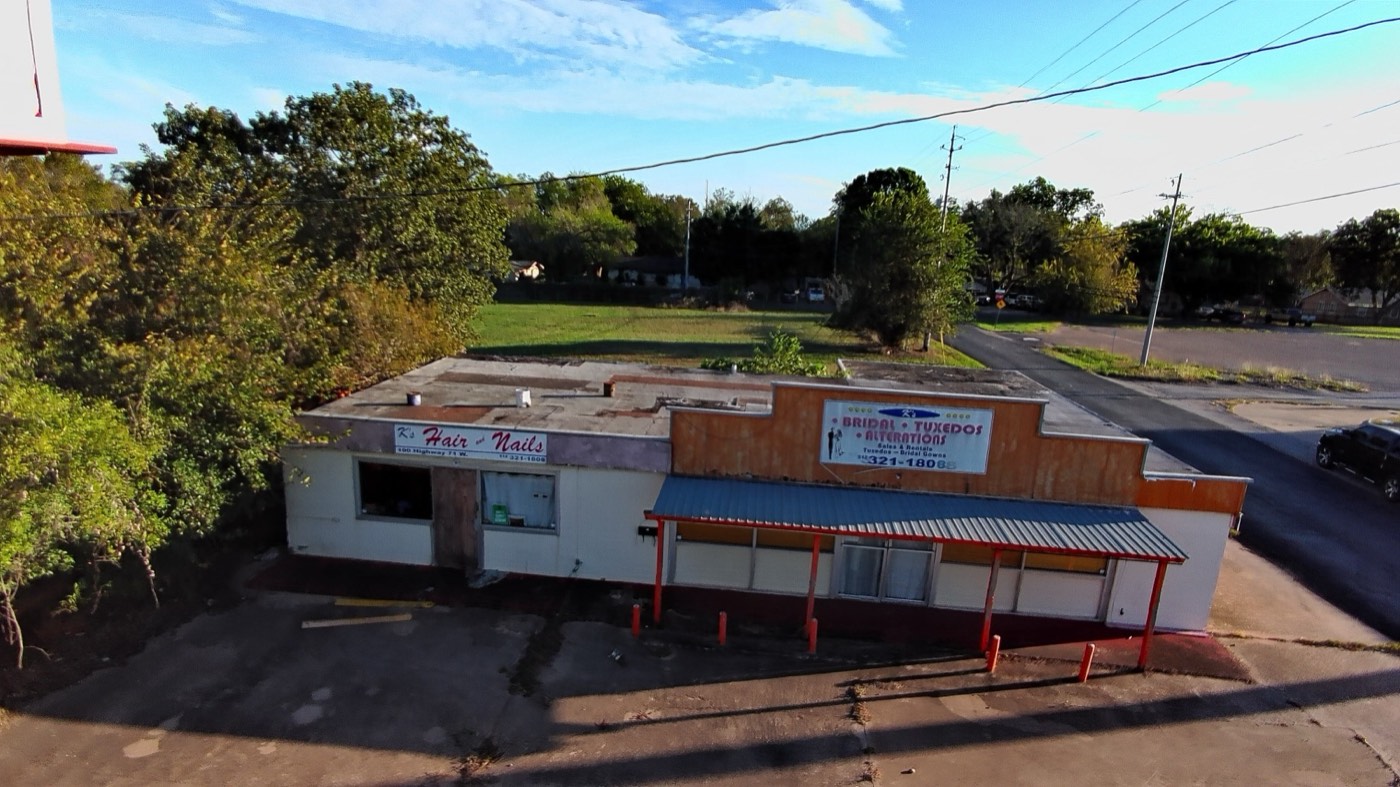 Aerial view of the existing building with the open lot and mature trees behind it