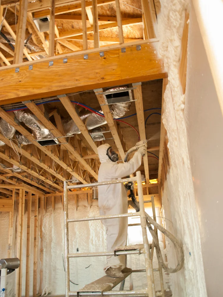 Technician applying intumescent fire-resistant coating to ceiling in Panama City FL by Blue Line Insulation