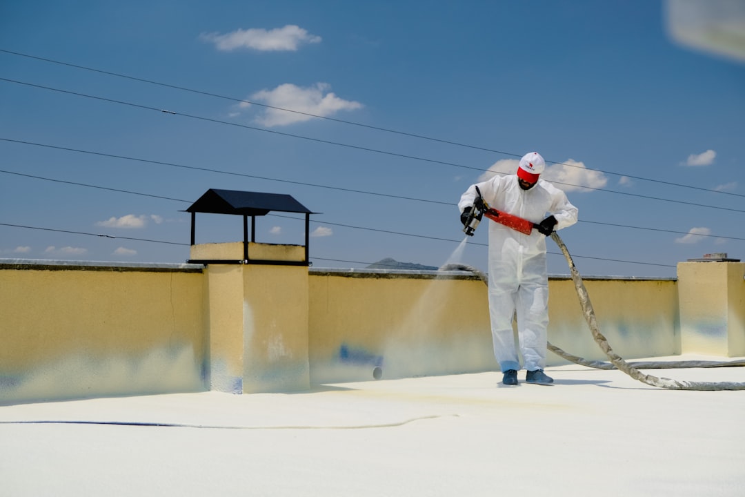 Technician applying intumescent coating to flat roof for fire protection in Panama City FL