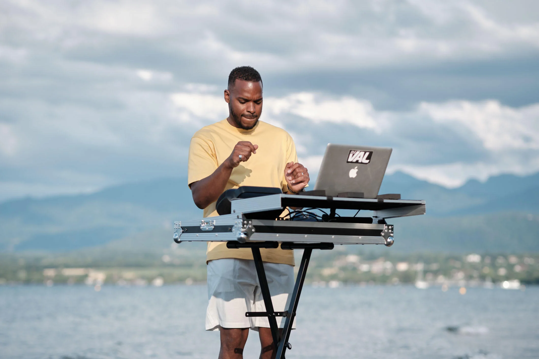 DJ en prestation en extérieur au bord du lac près de Genève, avec les montagnes en arrière-plan.