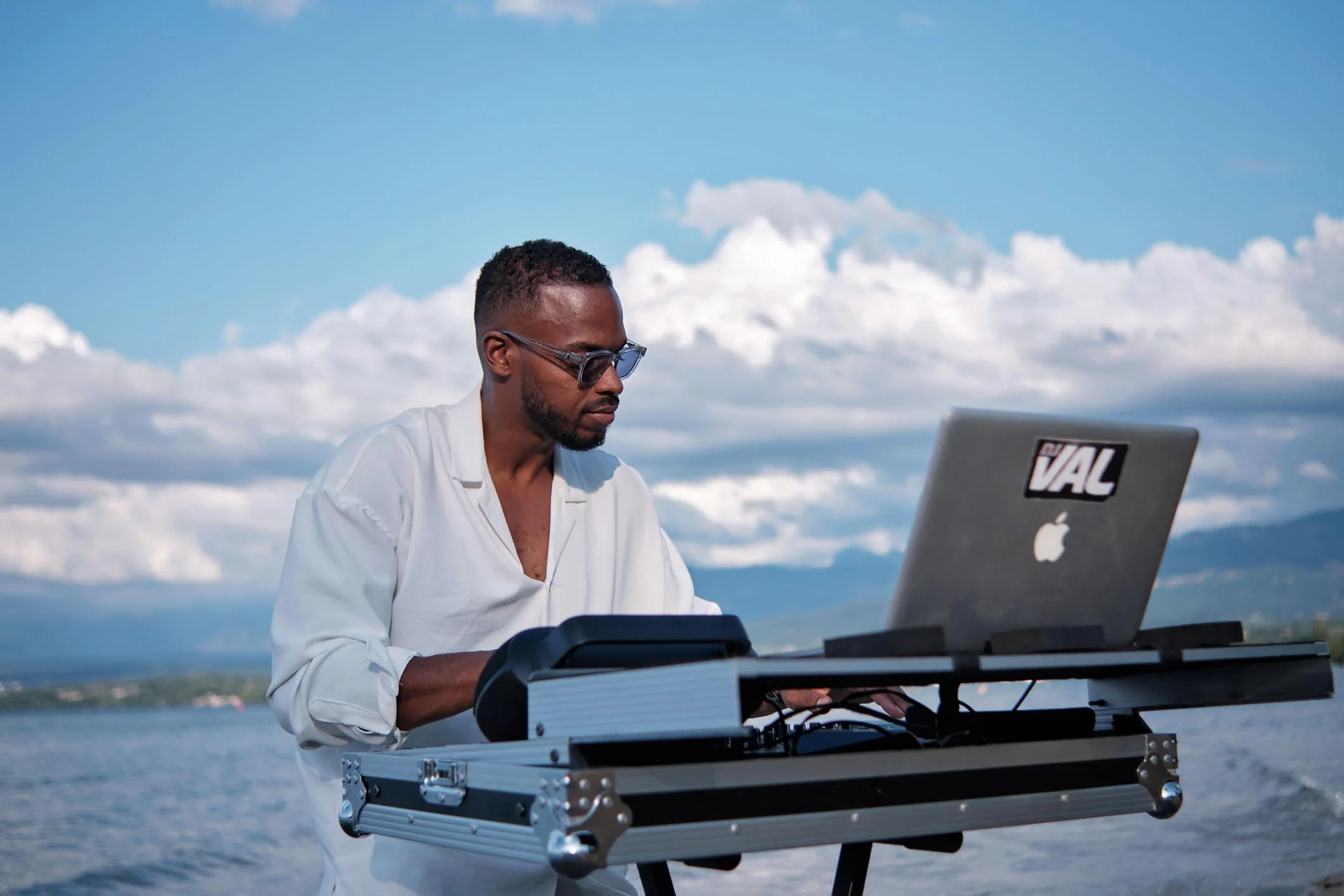 DJ en prestation en extérieur au bord du lac près de Genève, avec les montagnes en arrière-plan.