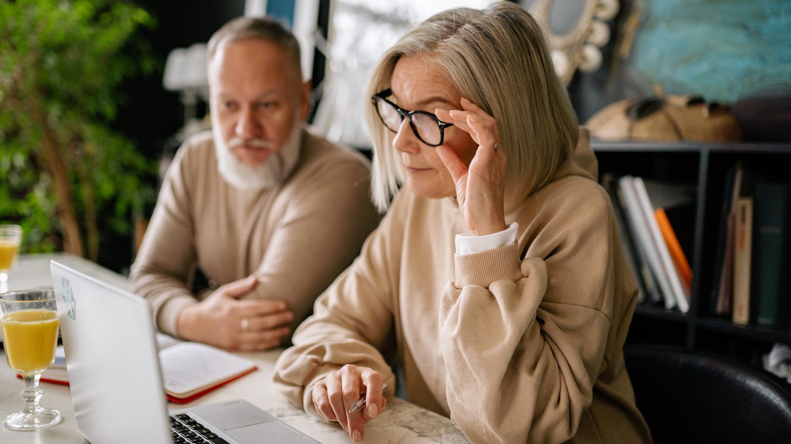 An older couple at a table reviewing Medicare options on a laptop together