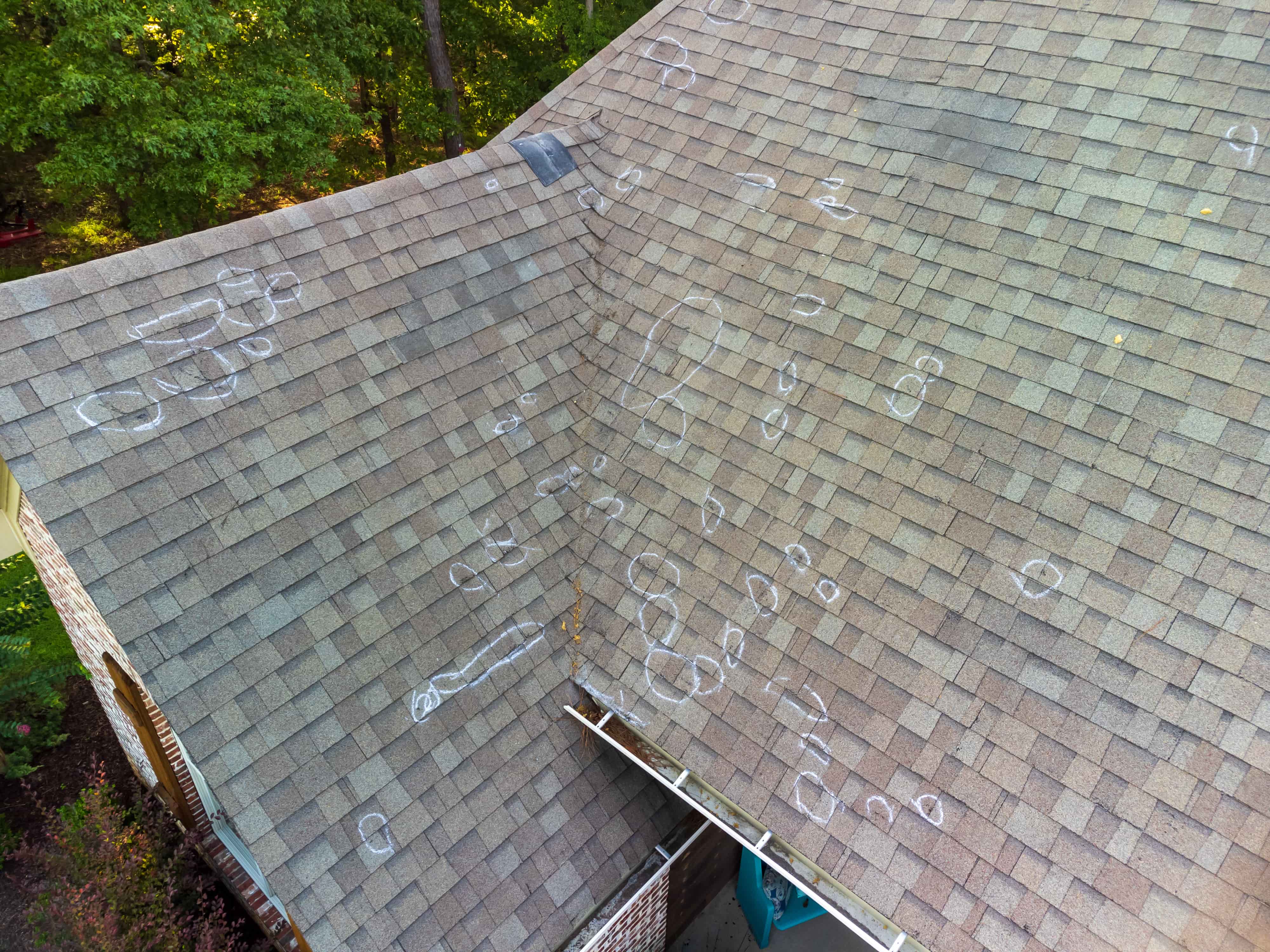 Asphalt shingle roof with chalk-marked hail damage identified during roof inspection. Asphalt shingle roof with chalk-marked hail damage identified during roof inspection.