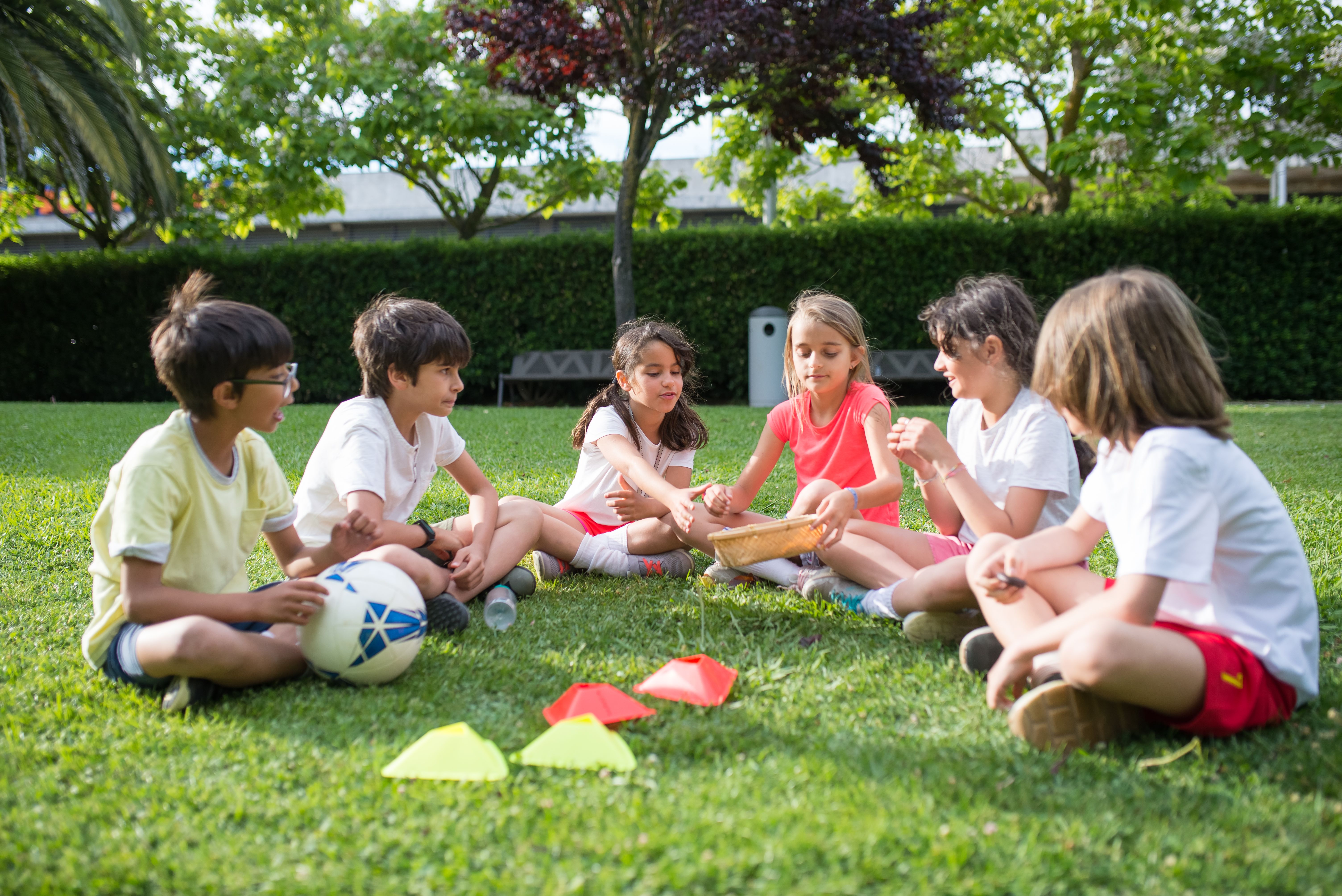 young soccer players sitting in circle with soccer ball