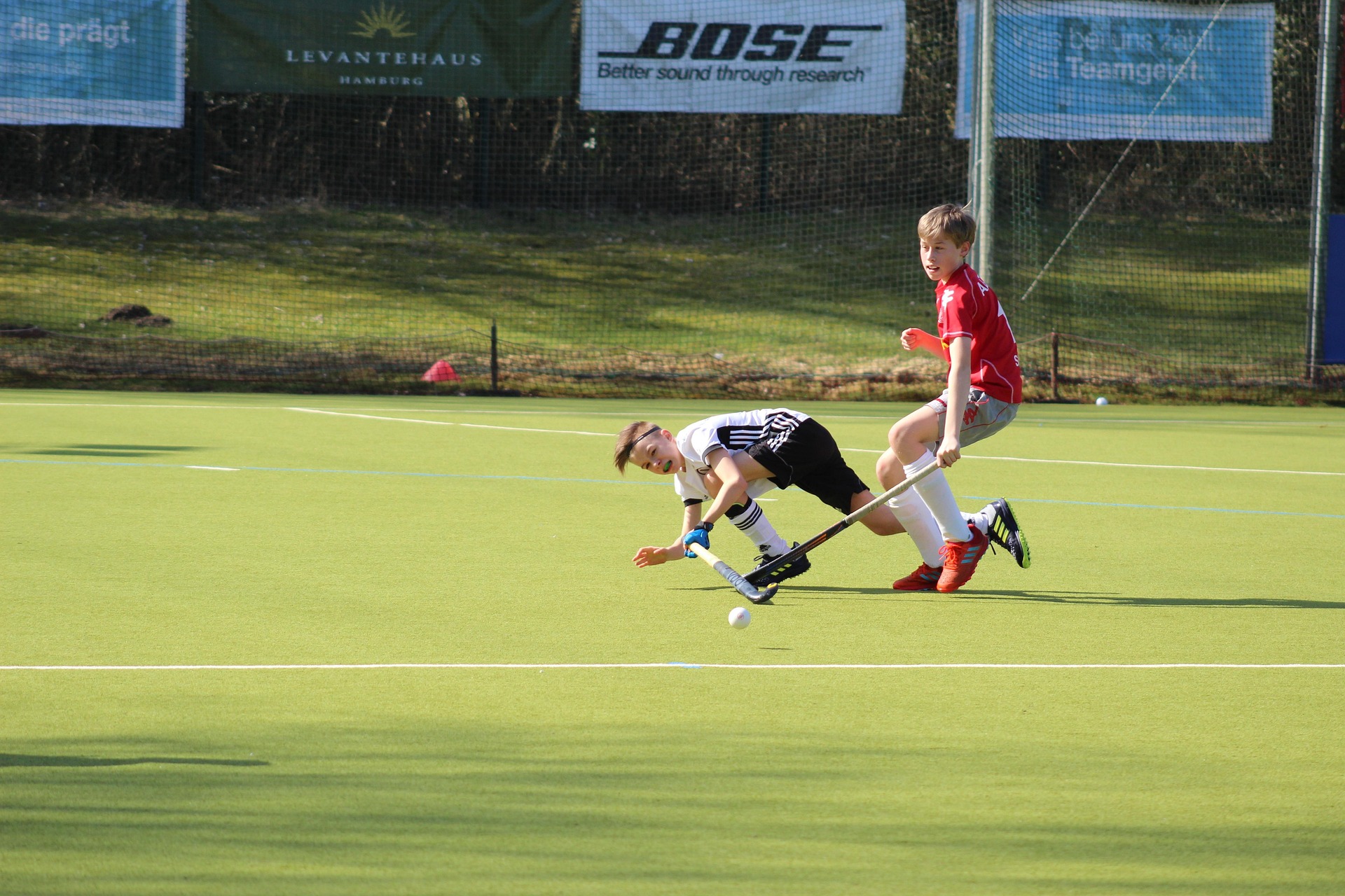 Junior field hockey players competing on an outdoor pitch