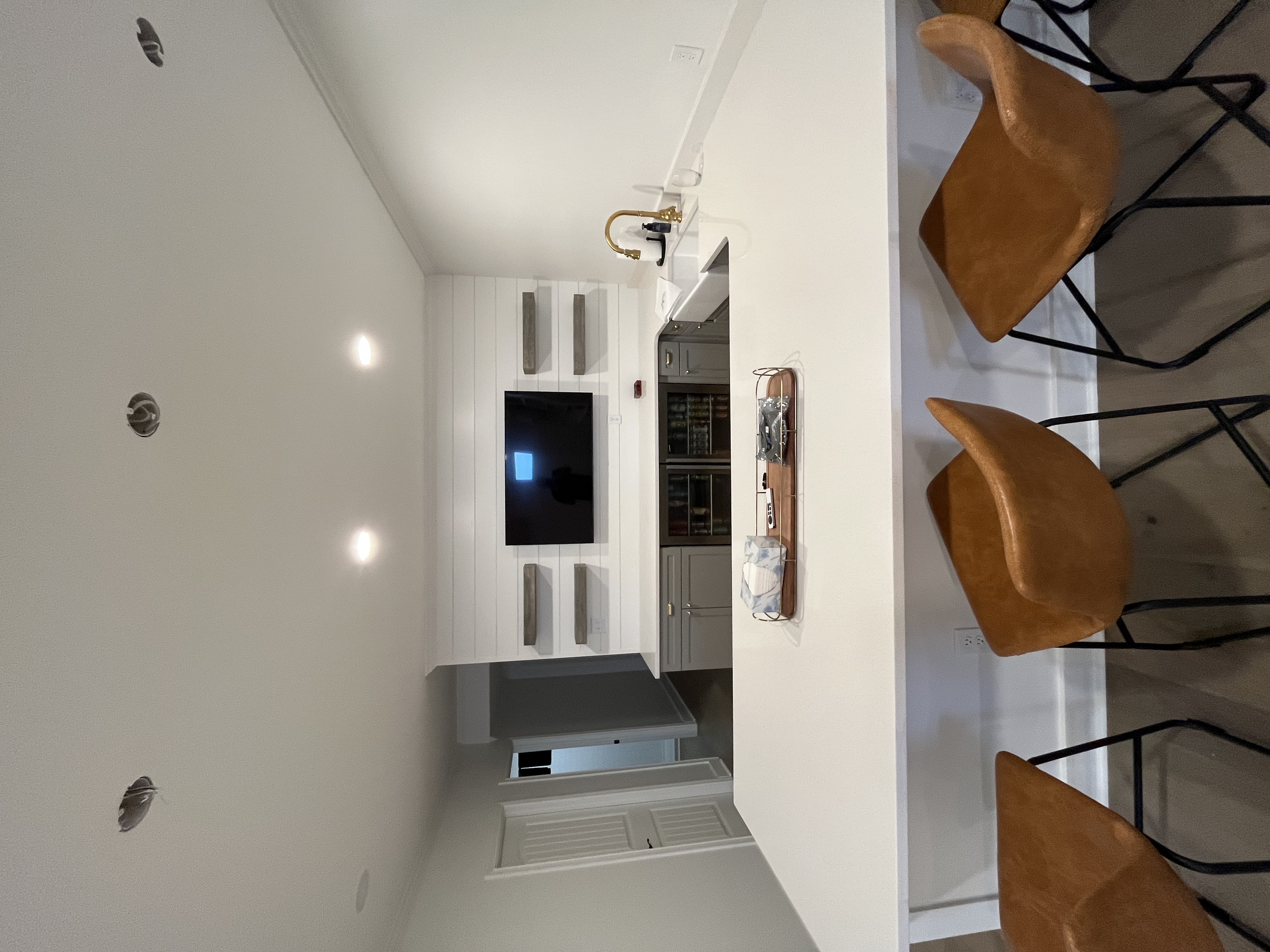 Open layout finished basement with custom entertainment center, white spindle staircase, and wide plank hardwood flooring