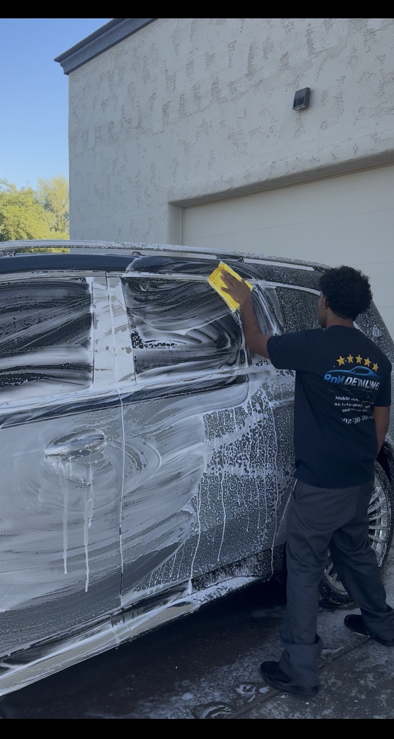 RnM Detailing team member washing a vehicle covered in foam