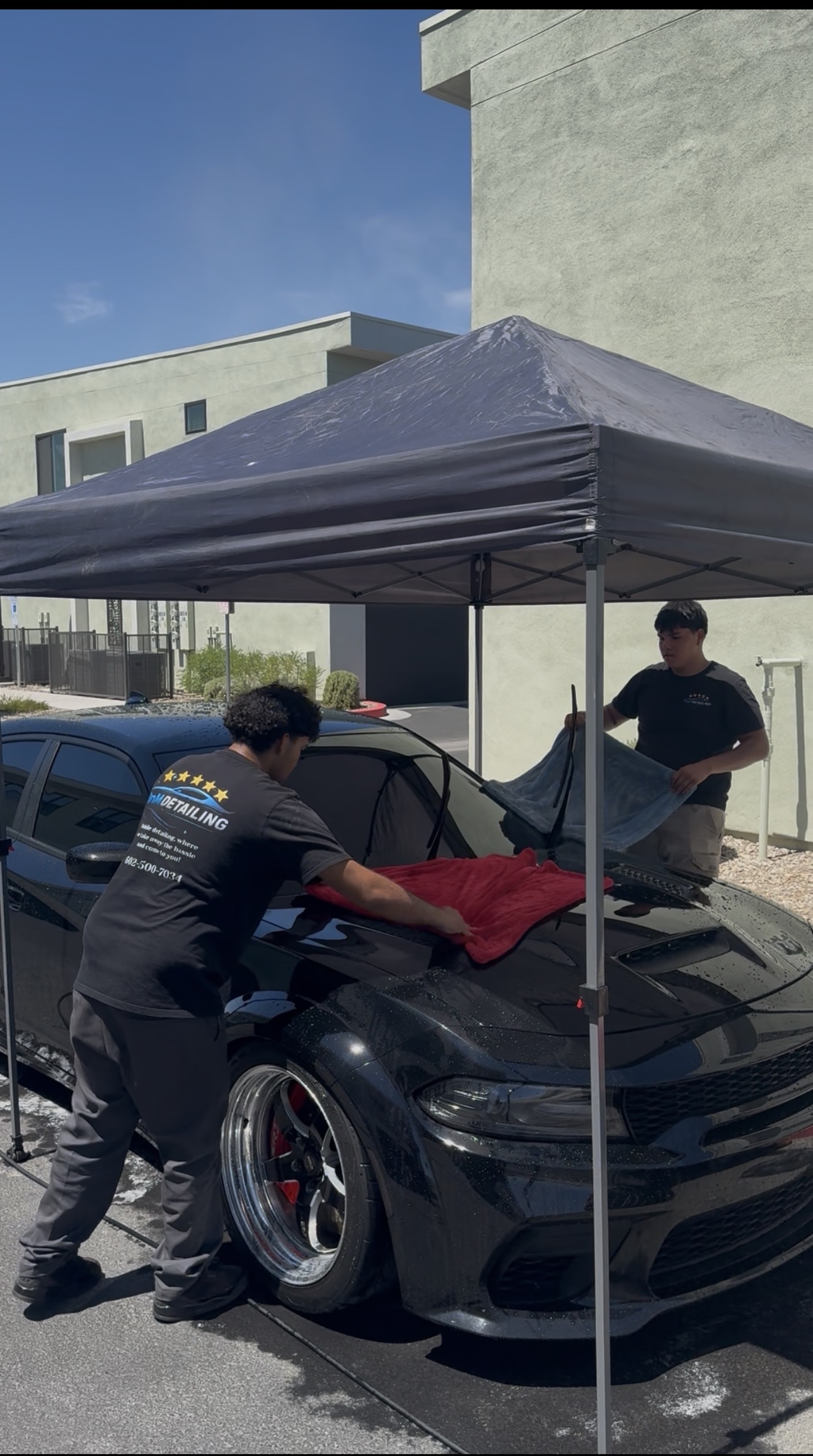 RnM Detailing team drying a Dodge Charger under a mobile canopy