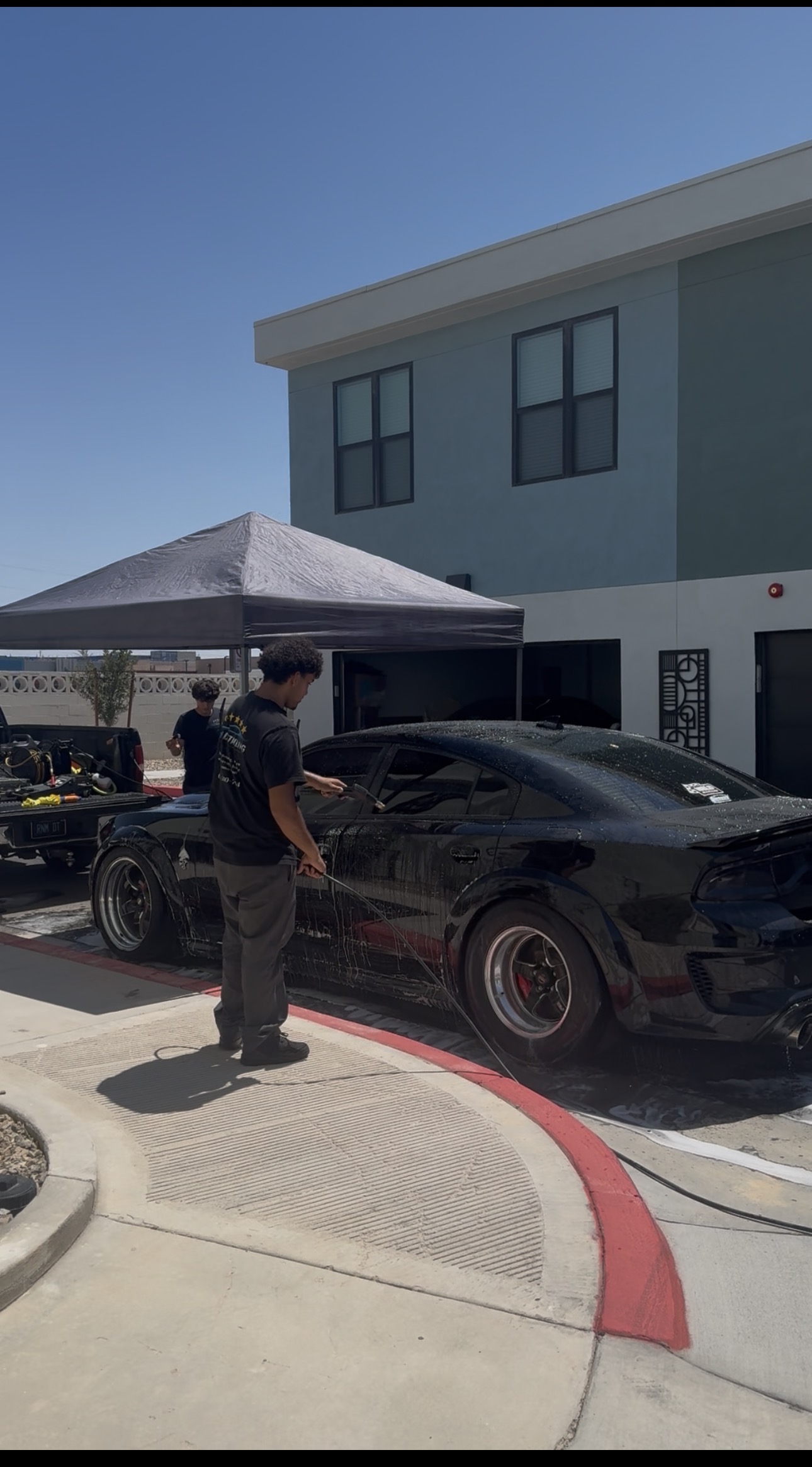 RnM Detailing team member rinsing a Dodge Charger