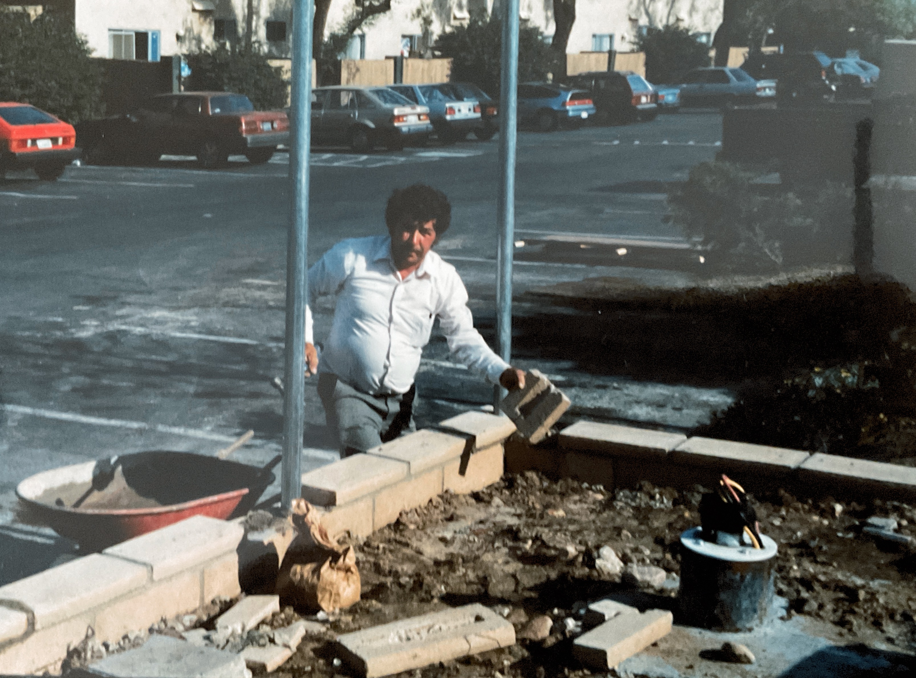 Santiago Gonzalez building a masonry wall during ALMA Gardening Company's early years